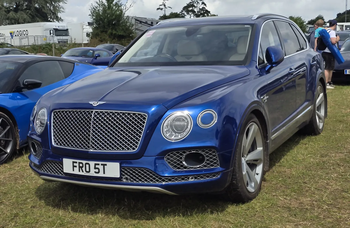 A blue Bentley Bentayga SUV parked on grass