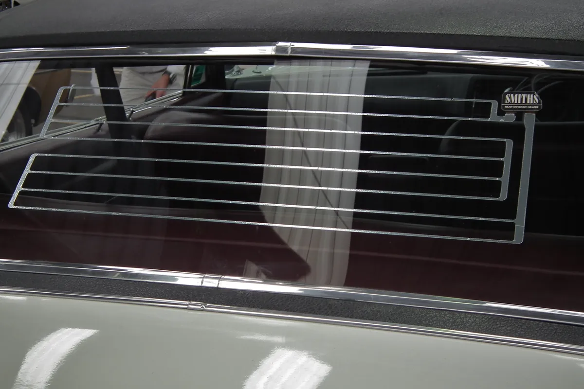 The thin lines of a defroster across the rear window of an old car