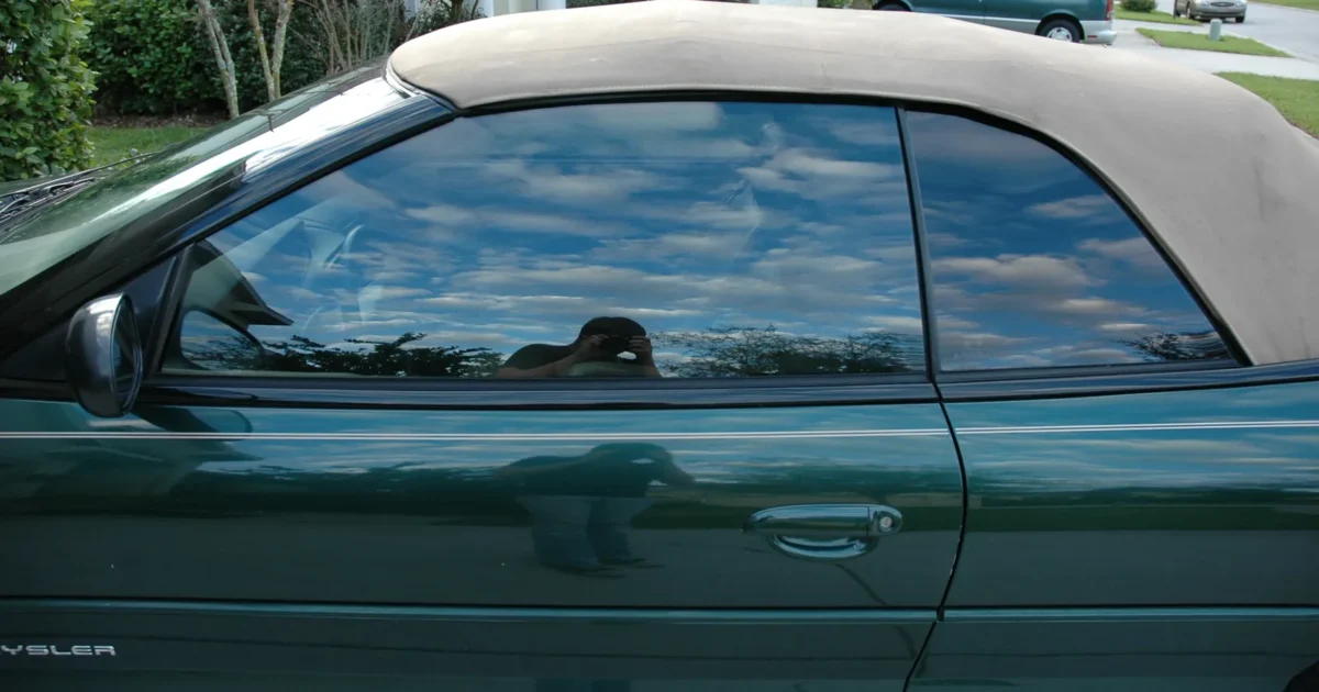 The side of a dark green convertible with dark tinted windows