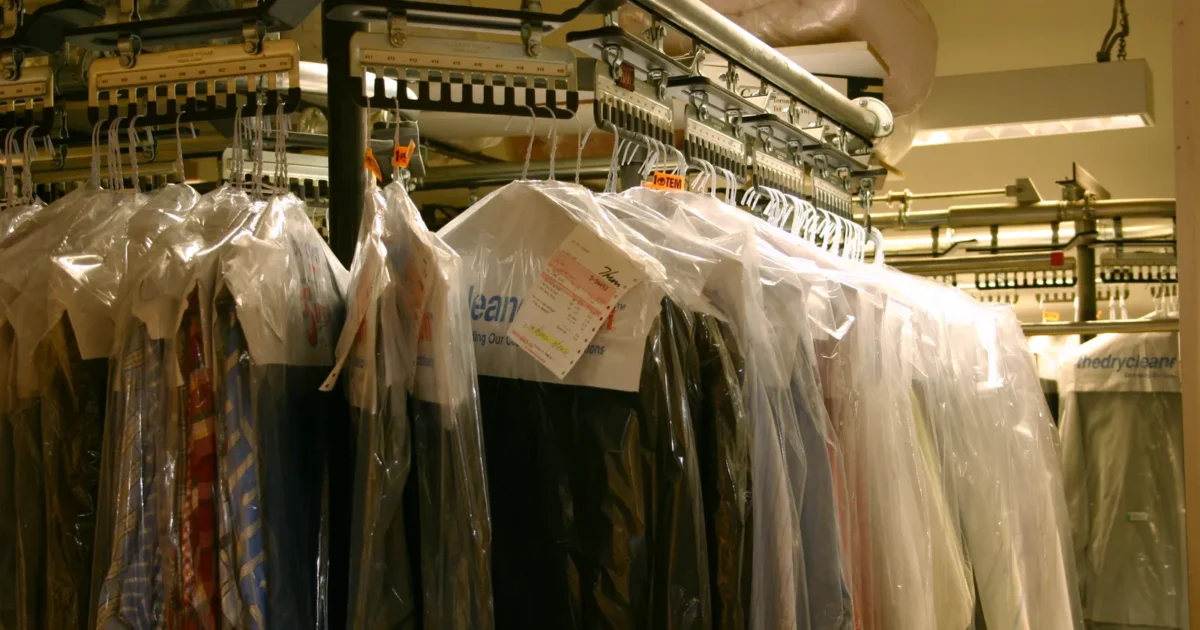 Rows of cleaned clothes in clear plastic bags hanging on a dry cleaner's rack