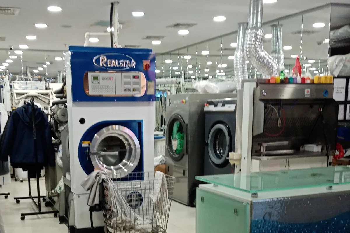 Inside a dry cleaning shop in a mall, with a dry cleaning machine and washers