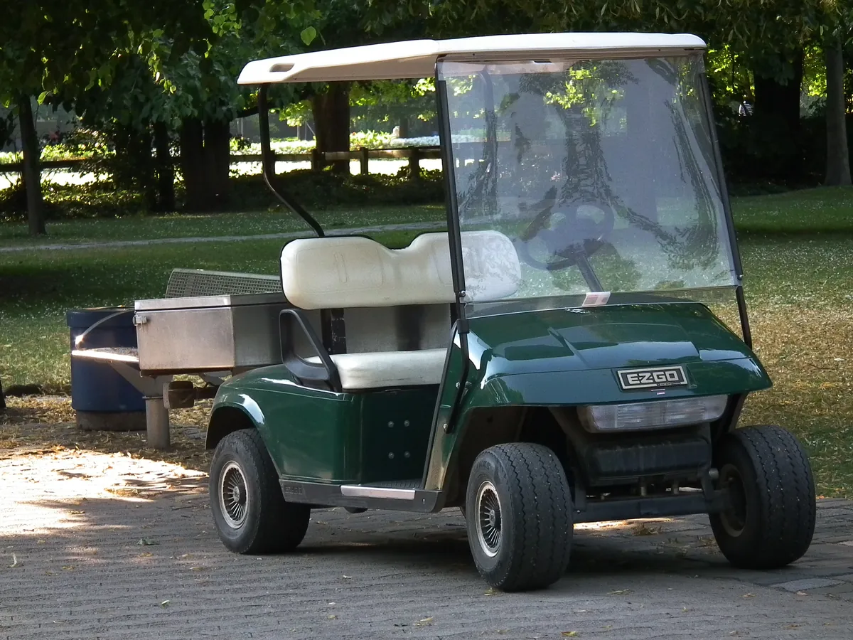 A dark green E-Z-GO two-seat electric golf cart in a park