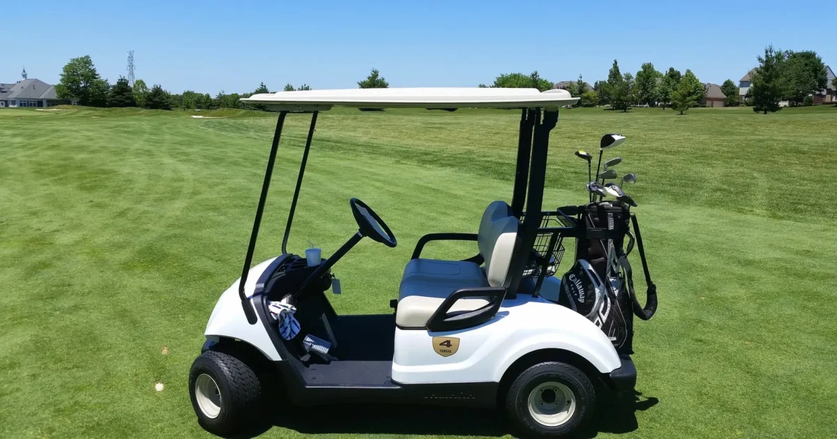 A white golf cart with a golf bag parked on a green fairway