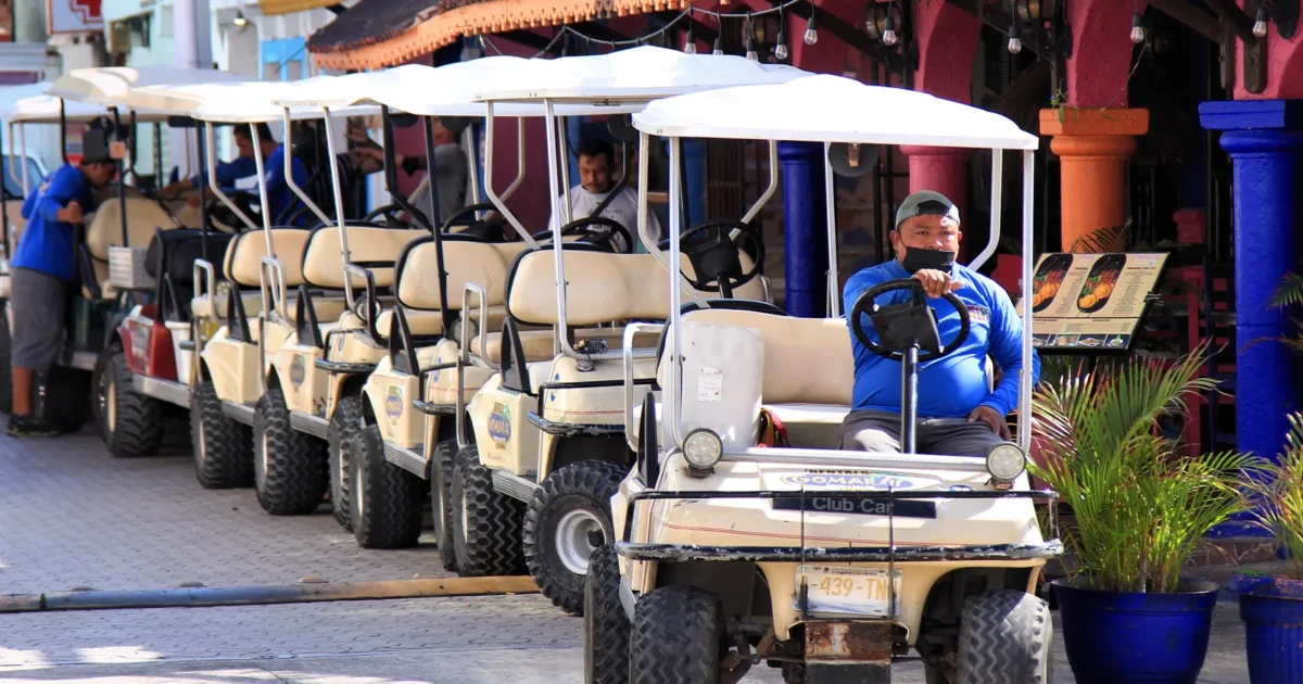 Workers getting a long row of rental golf carts ready on Isla Mujeres, Mexico