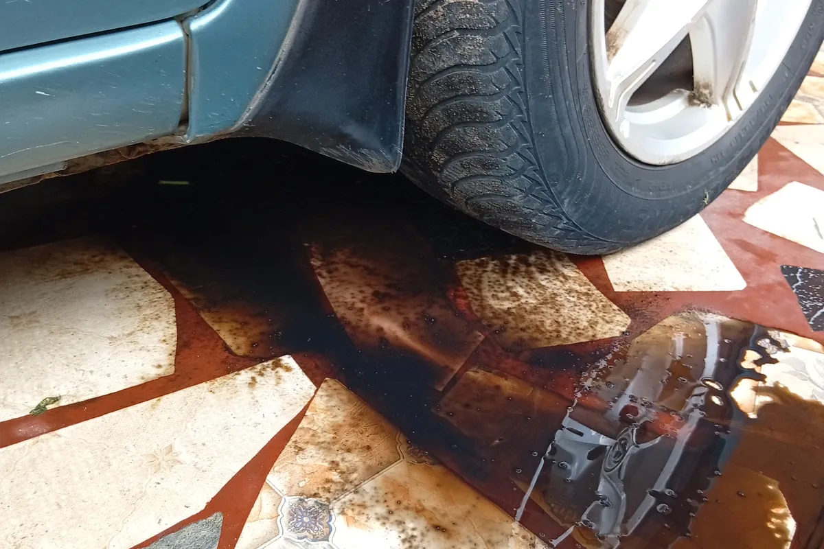 Dark oil spreading on the tiles under the front wheel of a car
