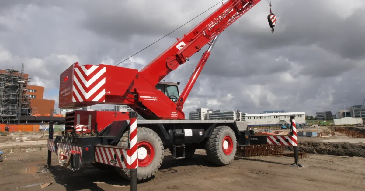 A red Grove rough terrain crane with its boom raised on a building site