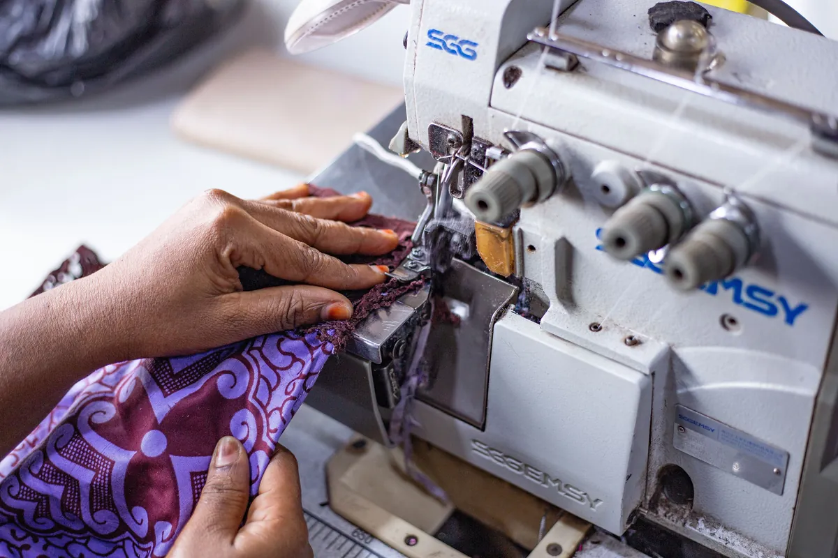 A tailor's hands guiding fabric through an overlock sewing machine