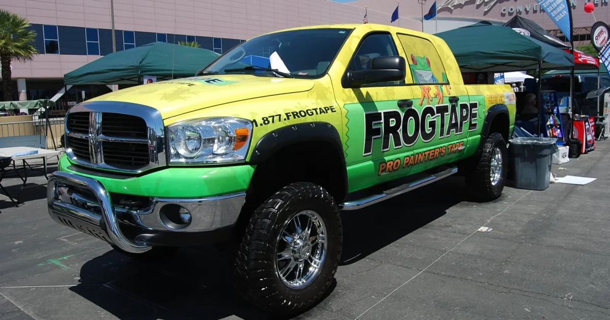 A Dodge Ram pickup truck in a full green and yellow wrap at a trade show