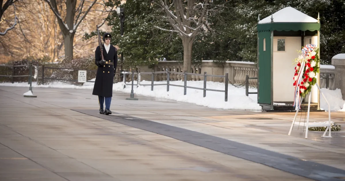 A Tomb Guard in a long coat at the Tomb of the Unknown Soldier on a snowy day