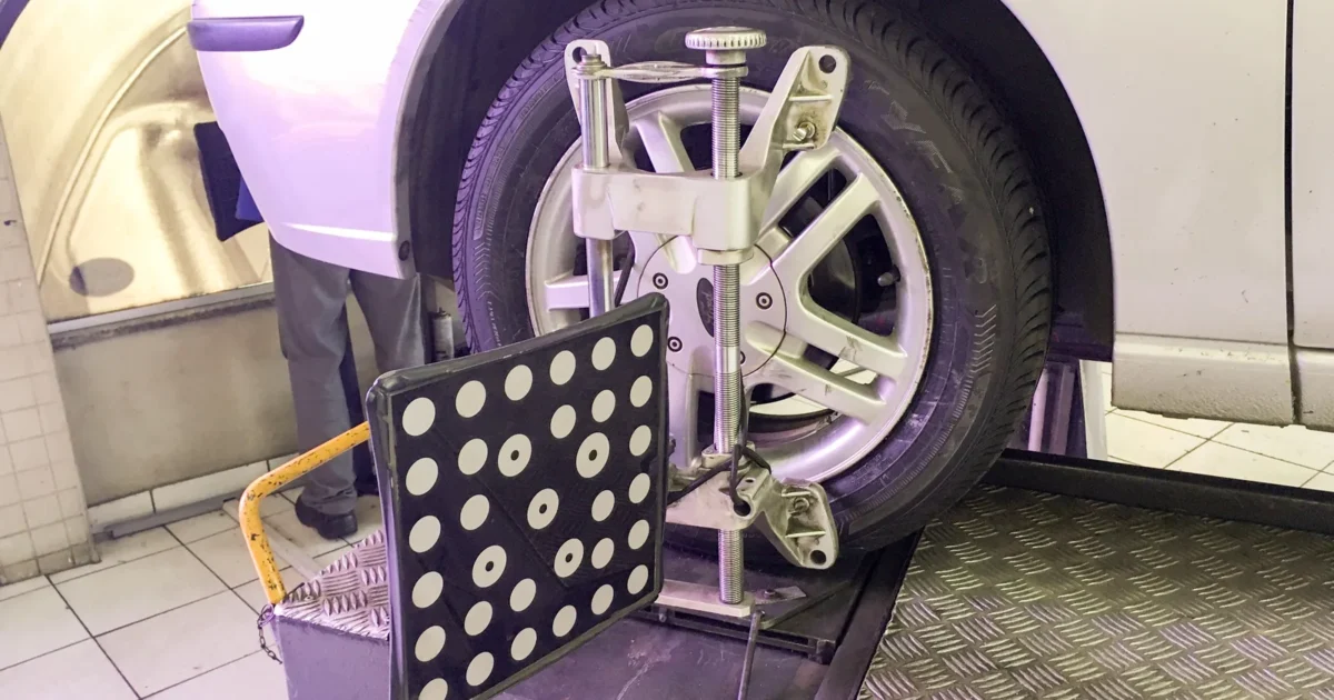 An alignment measuring target attached to the wheel of a silver Ford Focus on a workshop lift.