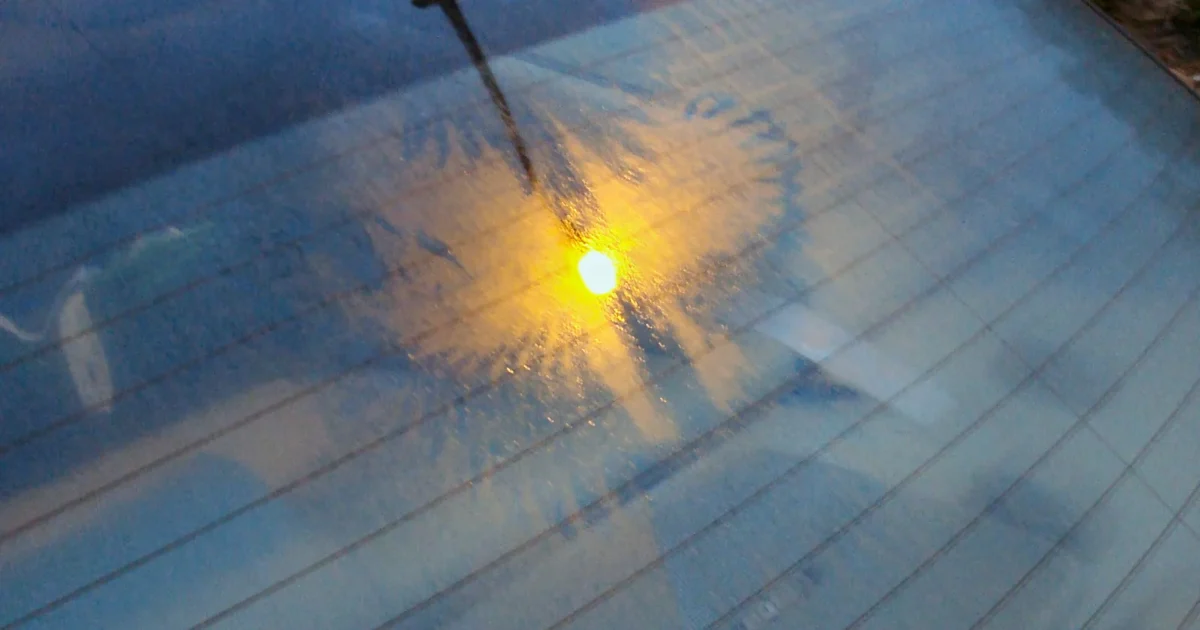 Close up of a car's rear window with fine horizontal heater lines and the rear wiper