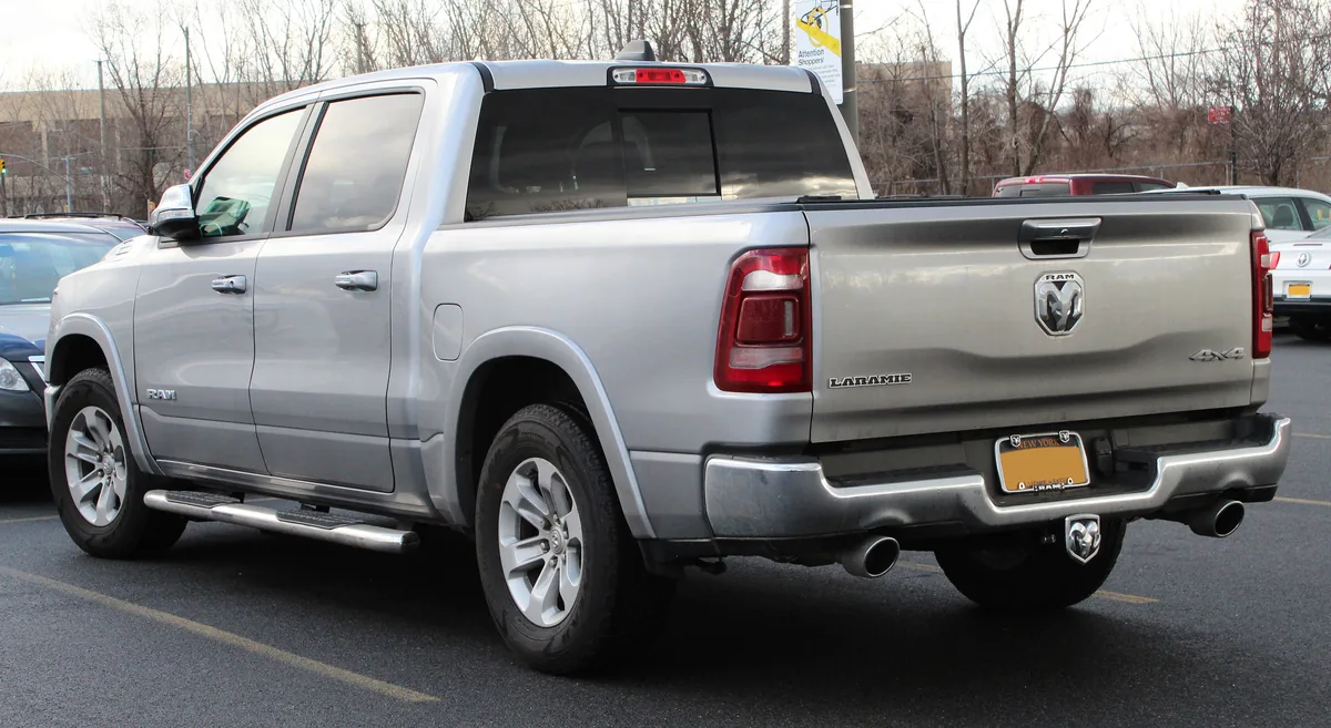 A silver 2019 Ram 1500 crew cab pickup seen from the back left, with its cab back window