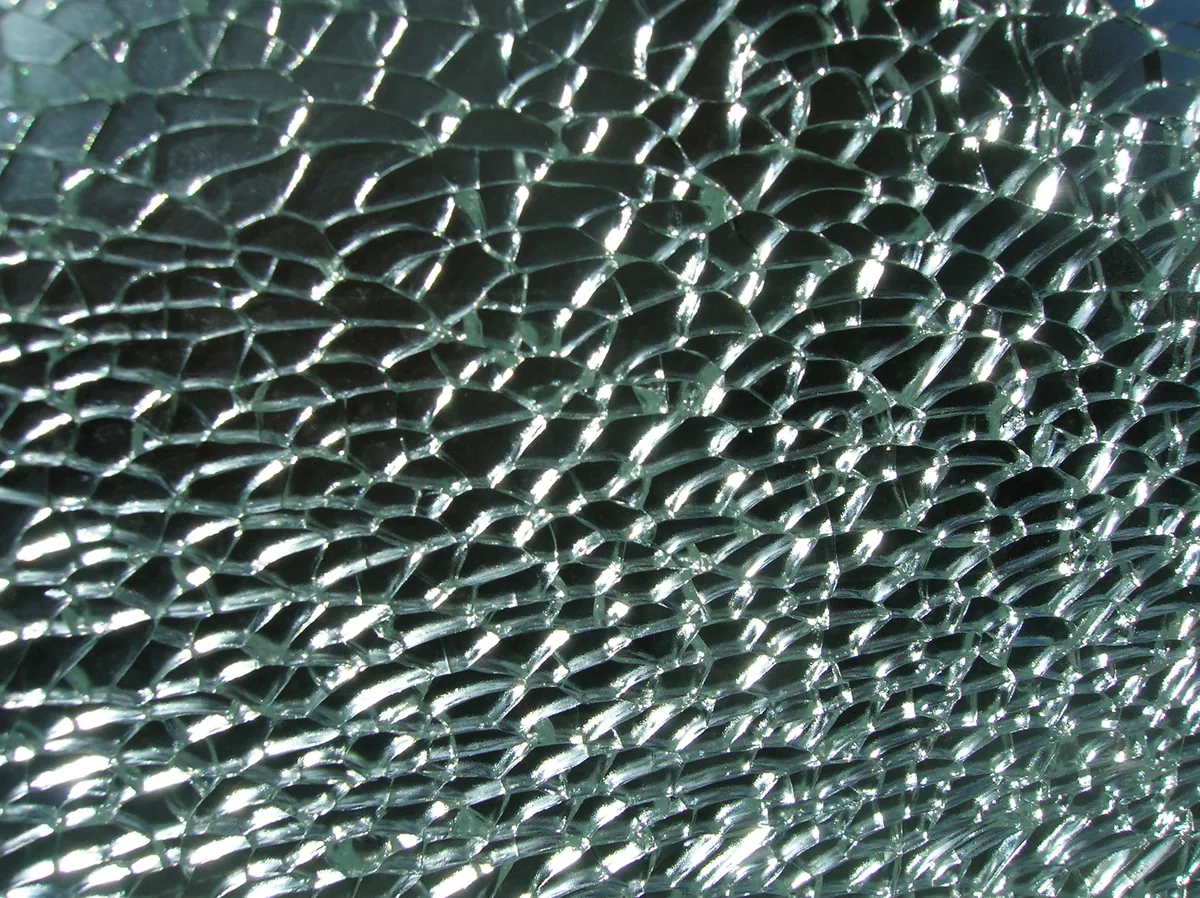 A car window broken into a web of many small pieces of glass that are still in place