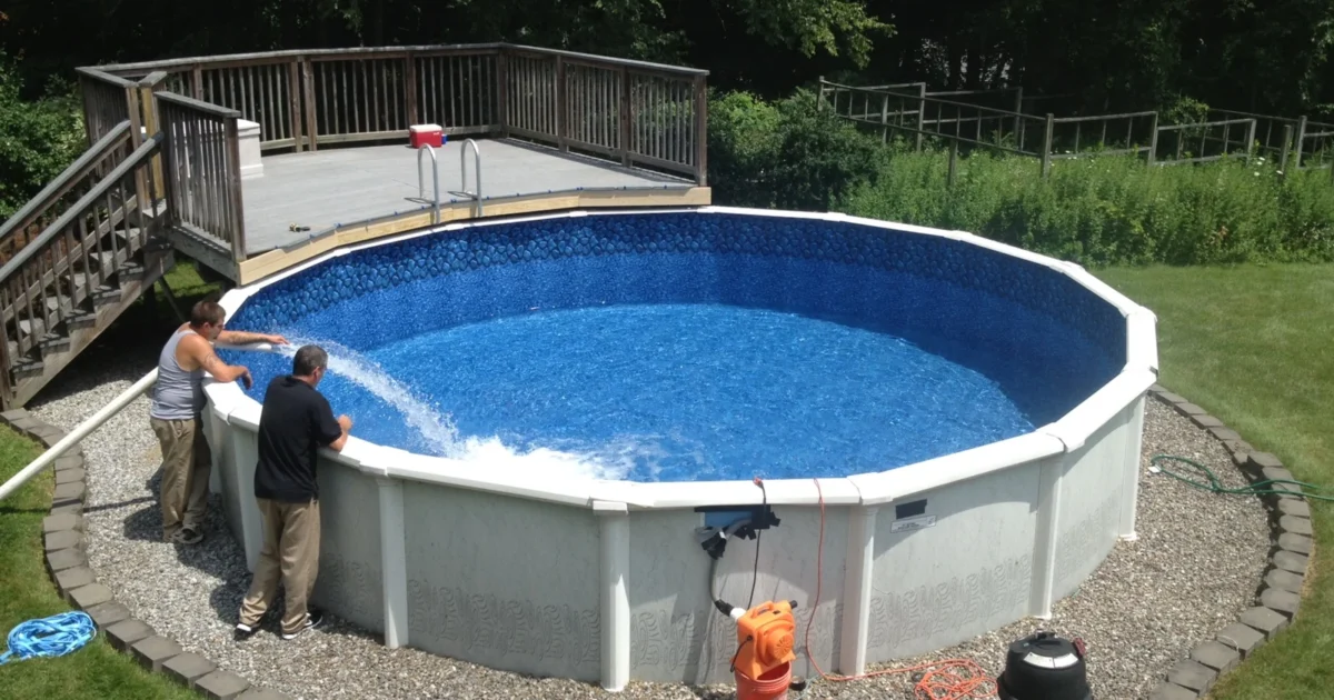 A round above-ground swimming pool with upright supports, a blue liner and a nearby wooden deck.