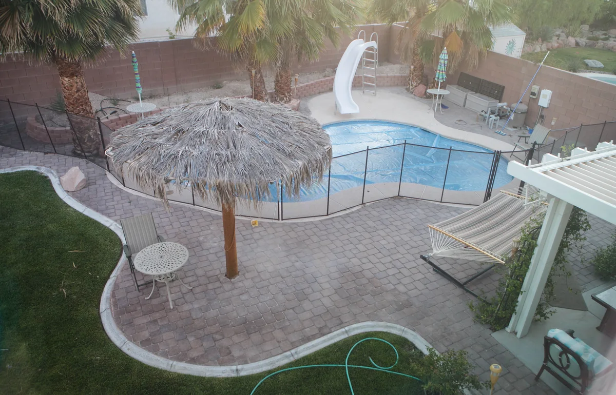An overhead view of a curved residential swimming pool and surrounding patio in Las Vegas.