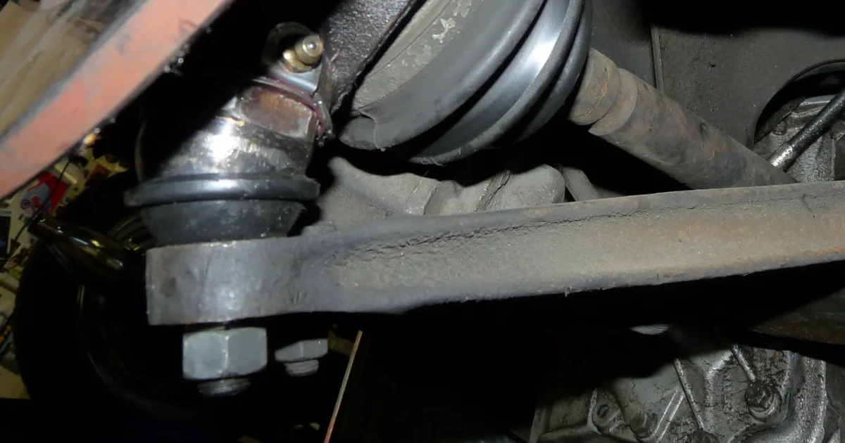 A ball joint at the end of a lower control arm, under the front of a car