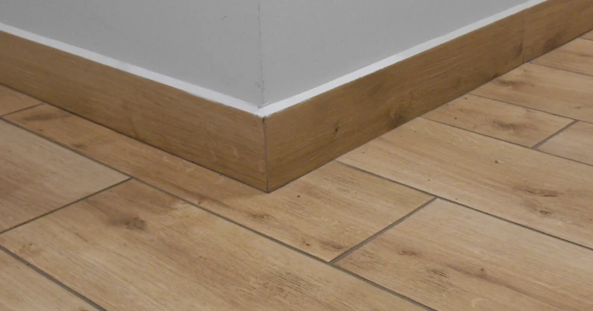 Wood baseboards joined around an outside corner above a wood floor.