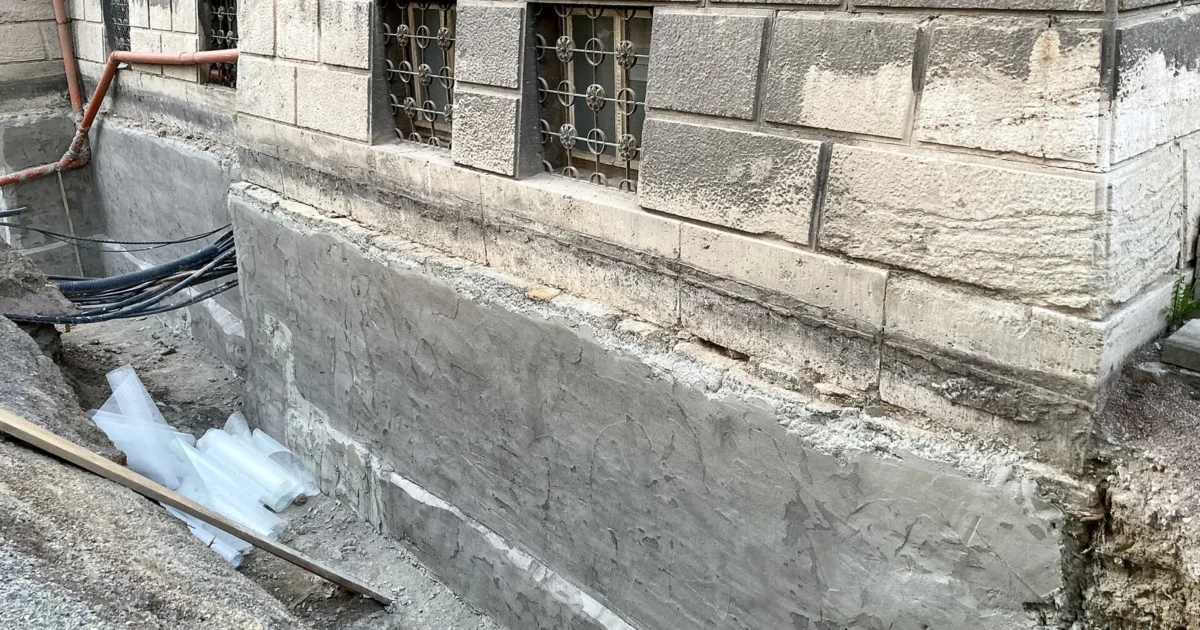 Exposed exterior basement wall being prepared for a waterproof coating.