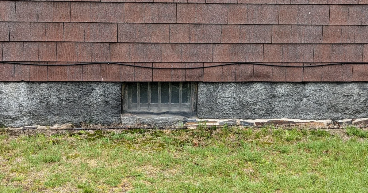 Small basement window in a stone foundation in Arlington, Massachusetts.