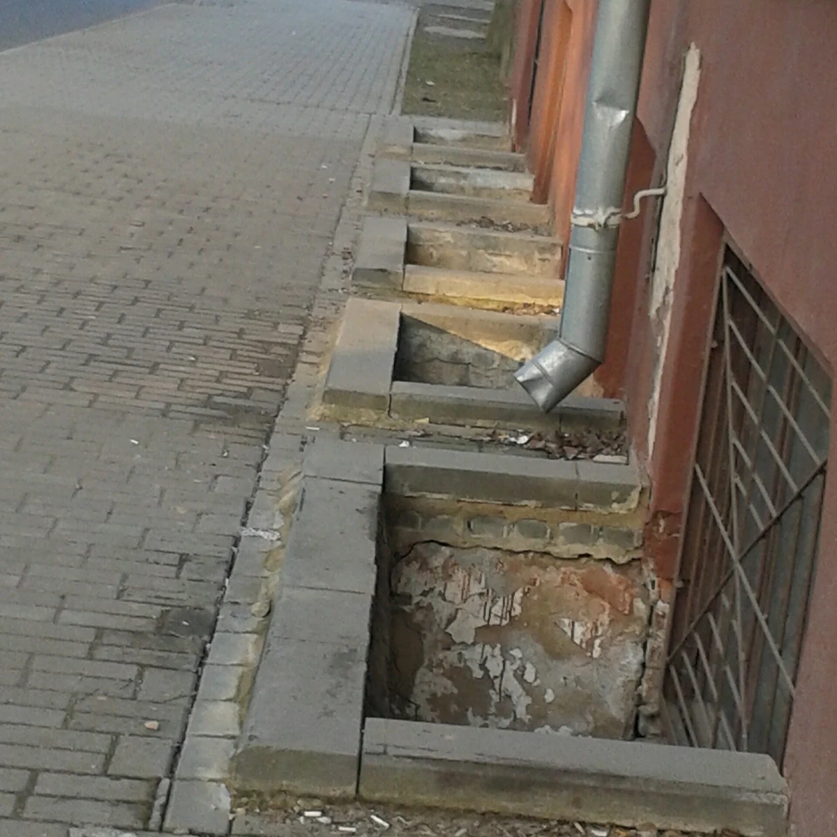 Open masonry wells alongside below-grade windows on a building.