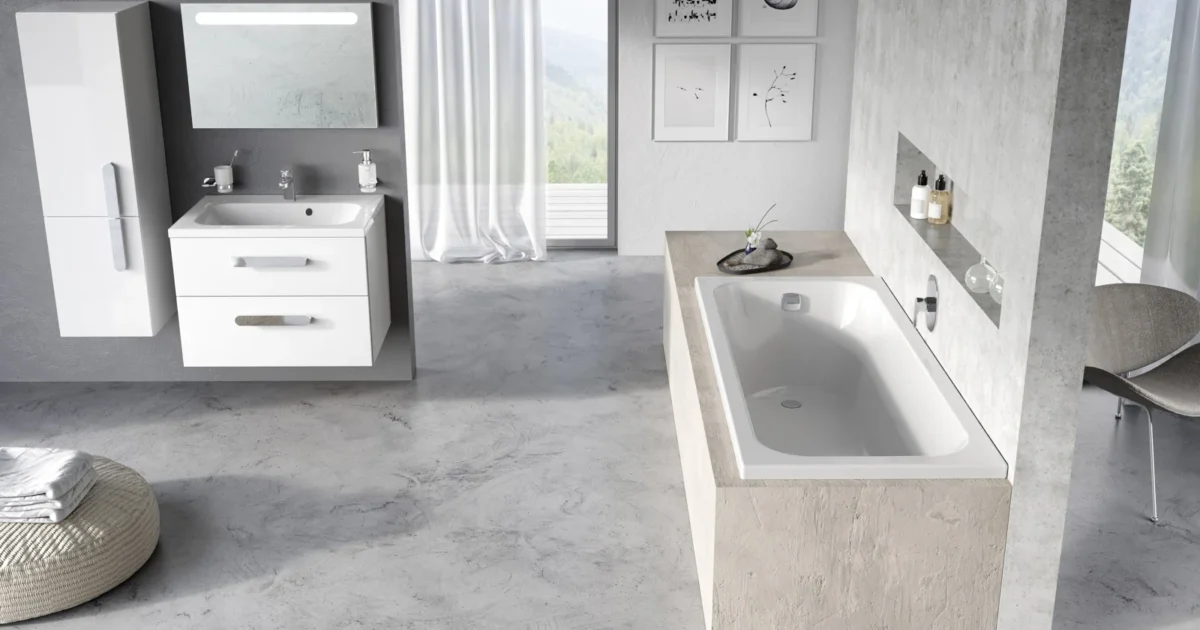 A fitted white bath in a tiled platform beside a washbasin.