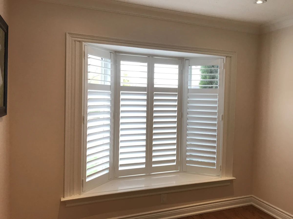 A bay window with fitted shutters and a broad interior shelf in Toronto.