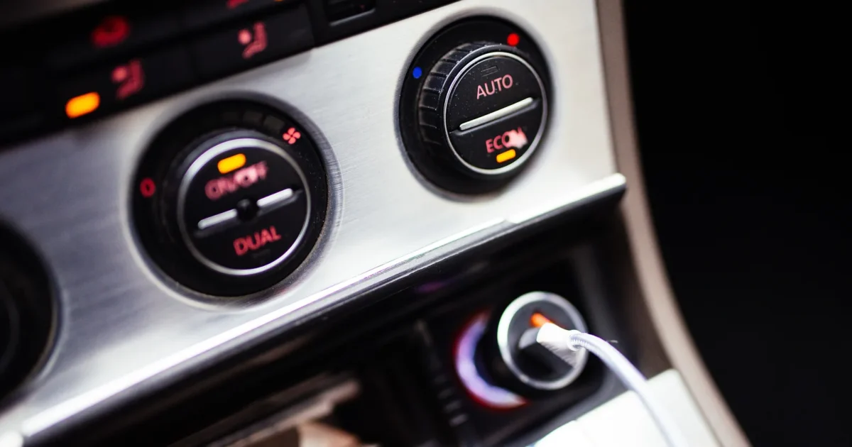 Two round climate control dials on a car dashboard at night, marked dual, auto and econ