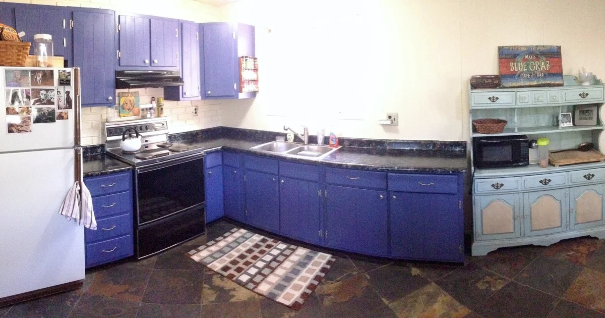 Kitchen with blue lower cabinets and wall cabinets, countertops and a stove.