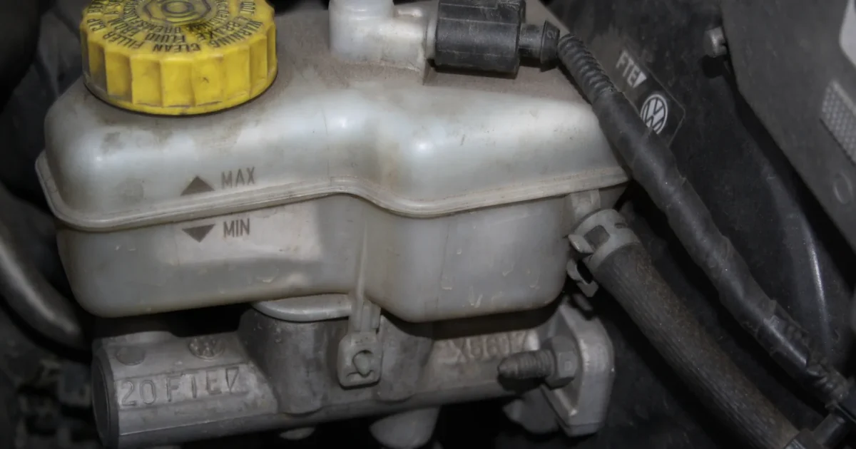 The brake fluid reservoir of a Skoda Fabia with a yellow cap, MAX and MIN marks on its side and the master cylinder below it
