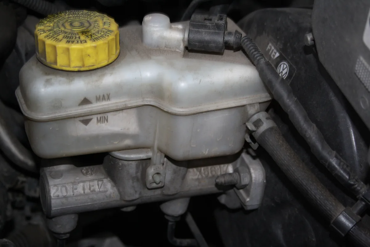 The plastic brake fluid reservoir of a Skoda Fabia, with a yellow cap and MIN and MAX marks, on top of the master cylinder