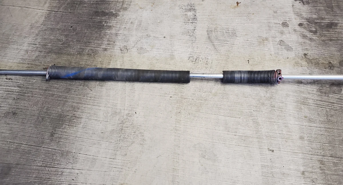 Removed torsion spring with a visible break between its coils.