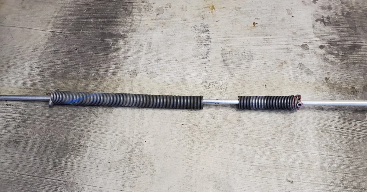 A removed garage-door torsion spring with a break separating the coils.