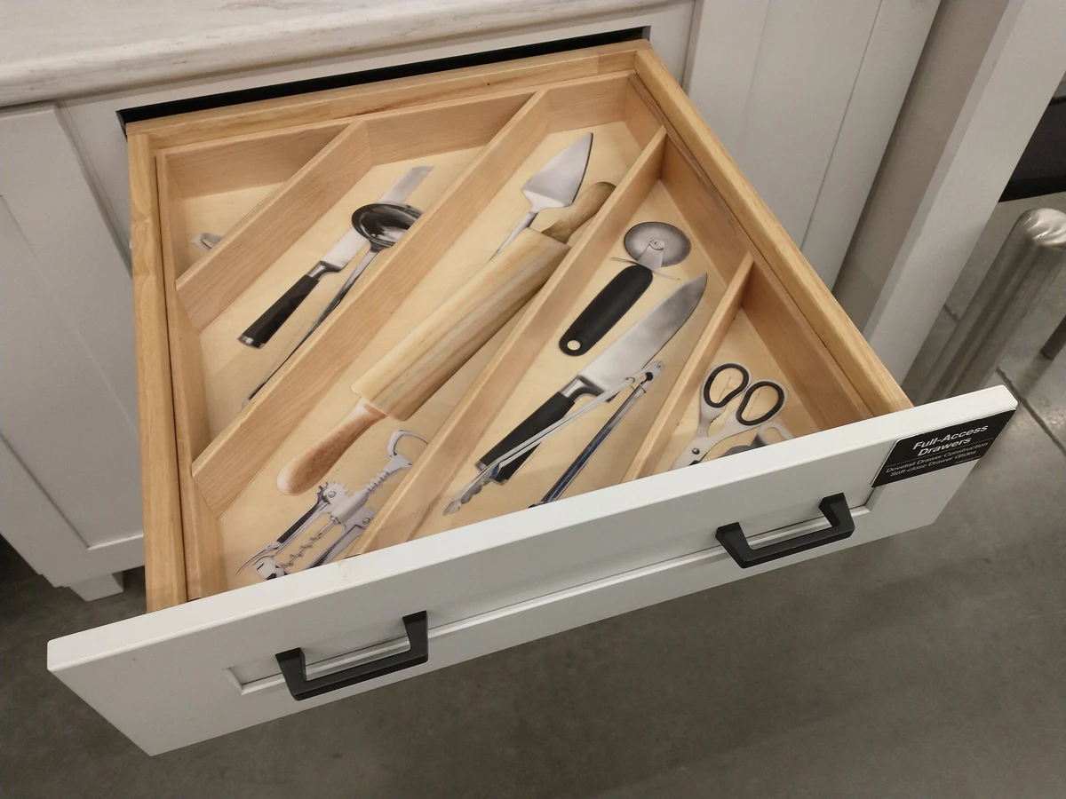 A cabinet showroom drawer with separate wooden utensil compartments.