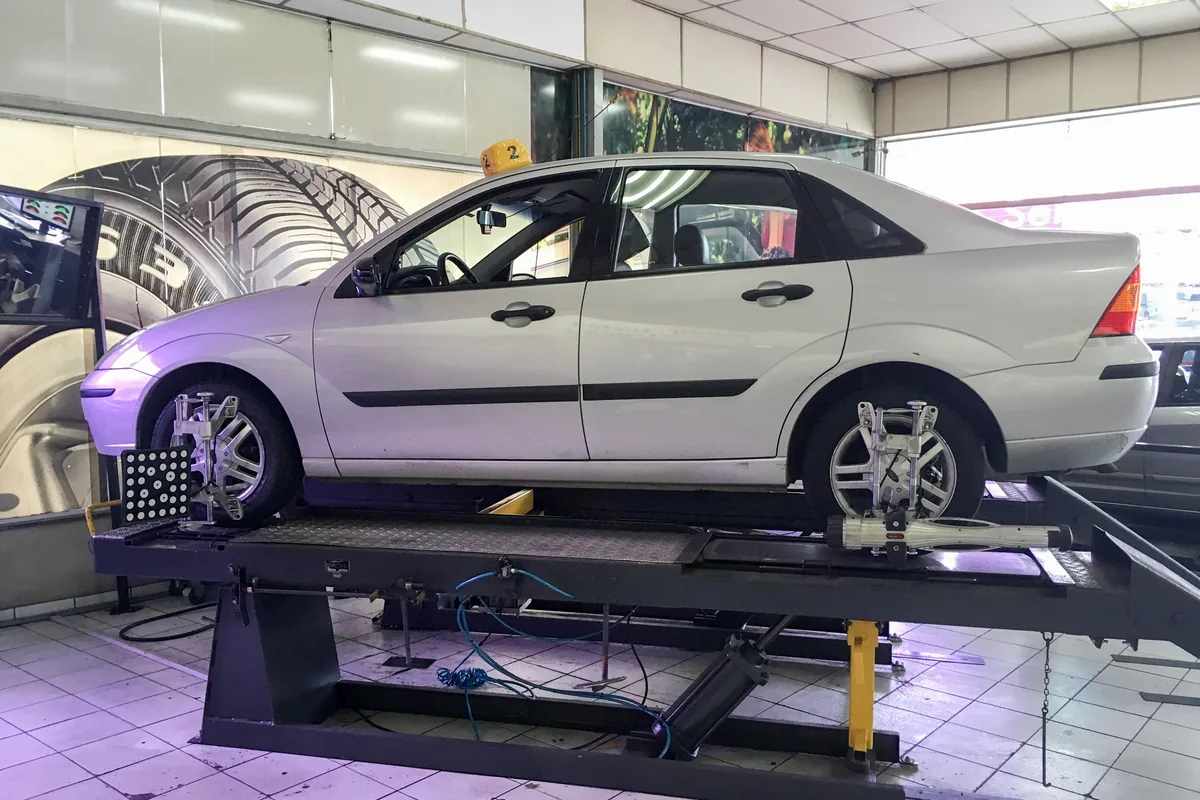 A silver Ford Focus standing on a raised alignment rack with measuring targets at its wheels.
