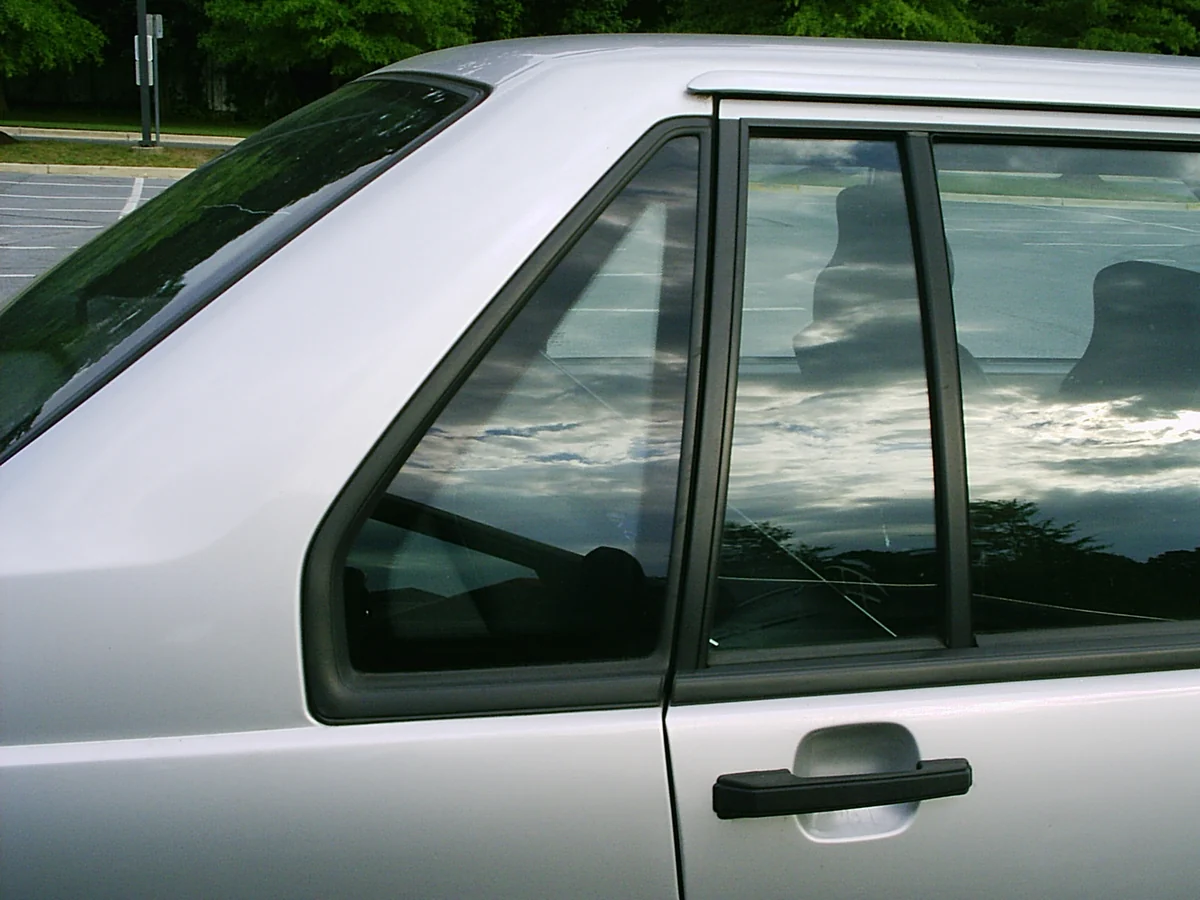 Two small fixed panes beside a larger rear door window on a silver car.