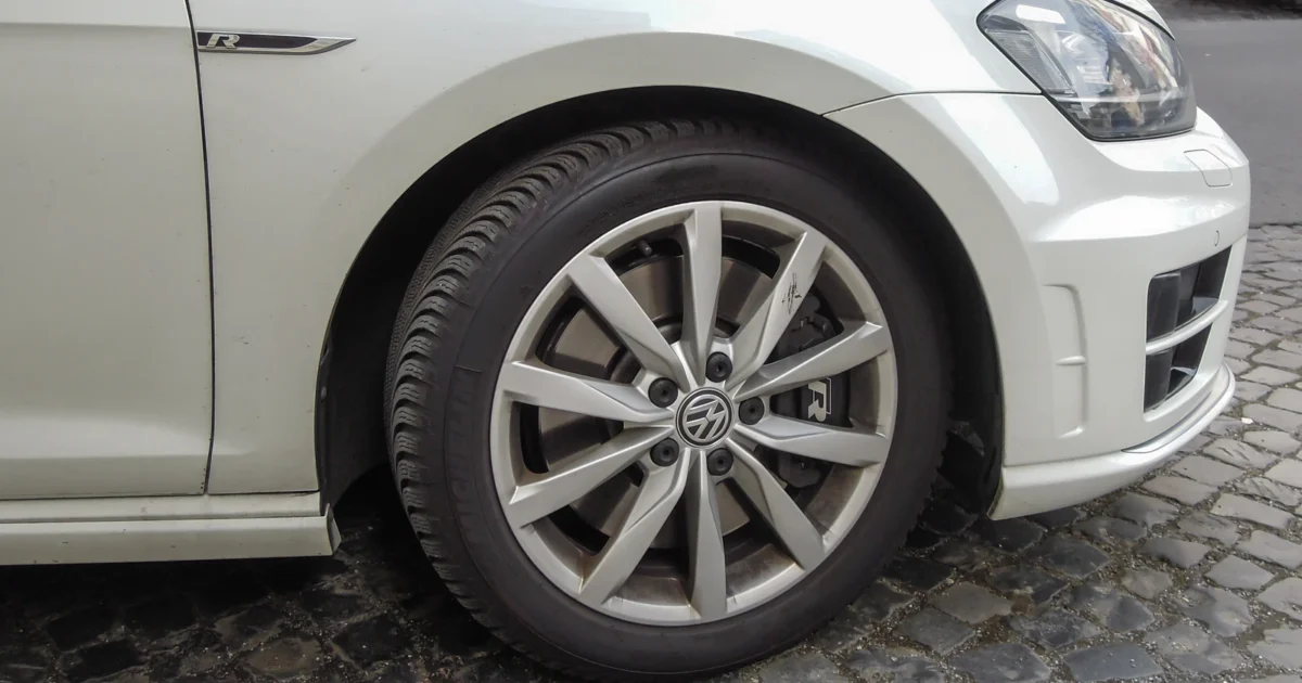 Front wheel and tire on a white Volkswagen, viewed from the side.