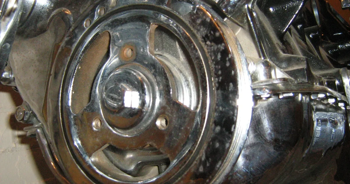A close look at a shiny chromed harmonic balancer at the front of an engine, with its hub, spokes and outer ring