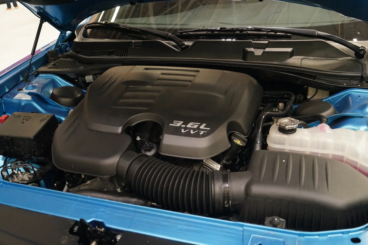 An open engine bay with a black engine cover marked 3.6L VVT and the intake tube in front of it
