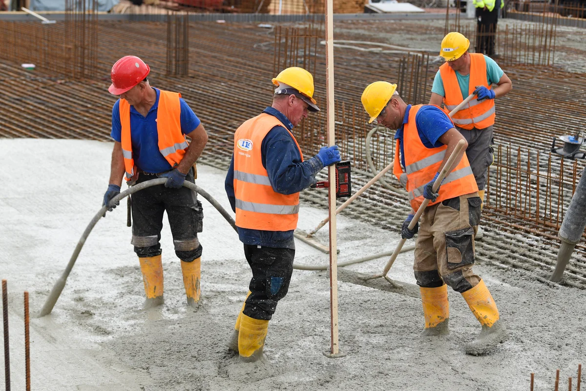 Workers leveling fresh concrete at a construction site.