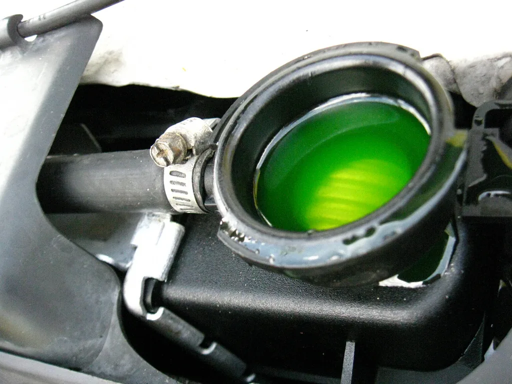 Bright green antifreeze seen through the open filler neck of a car radiator