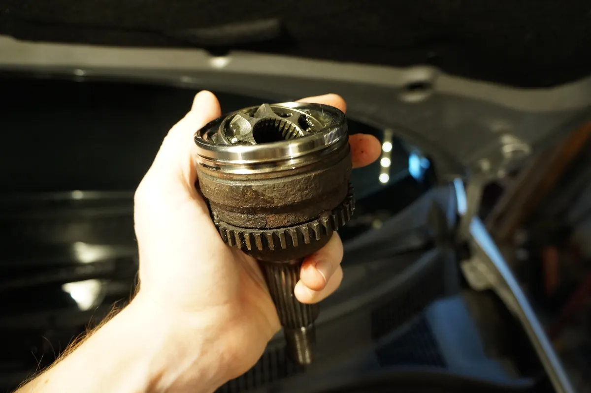 A worn CV joint held in a hand, with its ABS ring split