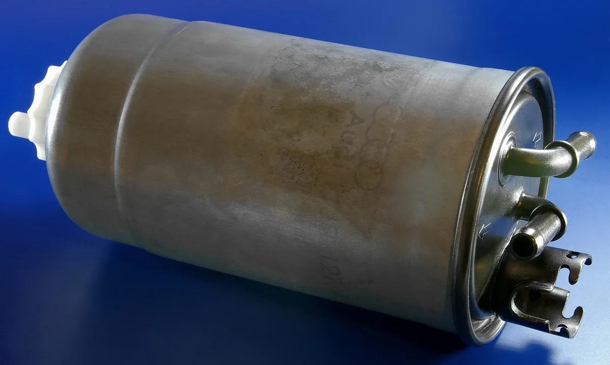 A metal Volkswagen-group diesel fuel filter canister on a blue background.