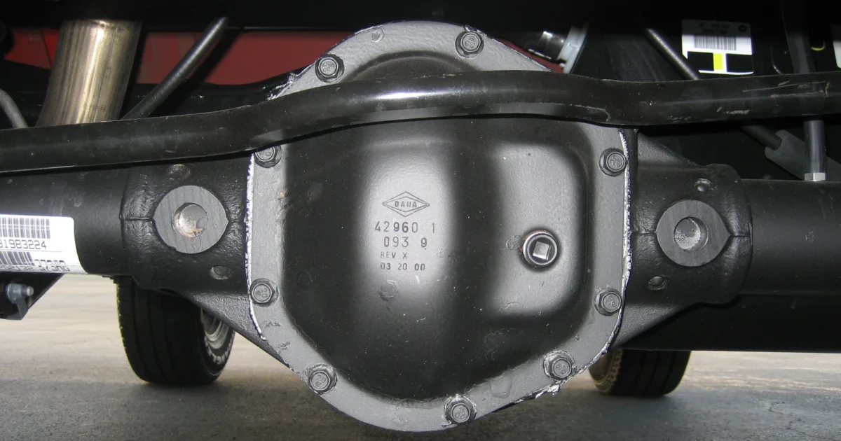 The black rear differential cover and axle beneath a Jeep.