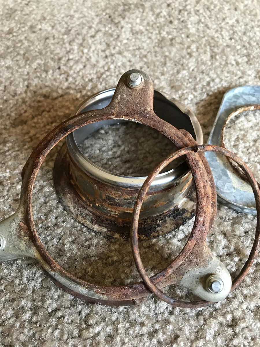 Removed disposal sink flange and mounting hardware showing heavy corrosion.