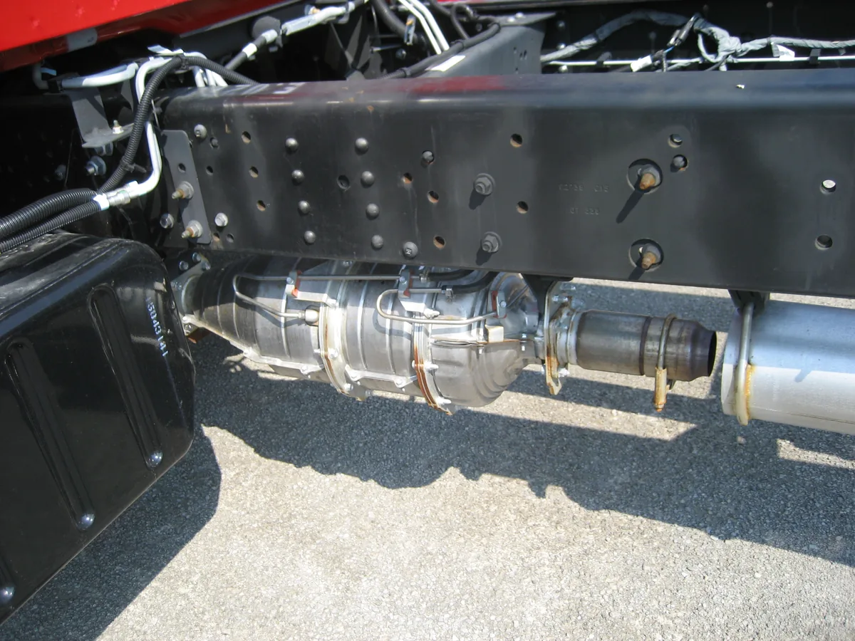 The exhaust under a truck frame, with a long silver particulate filter canister between the pipes