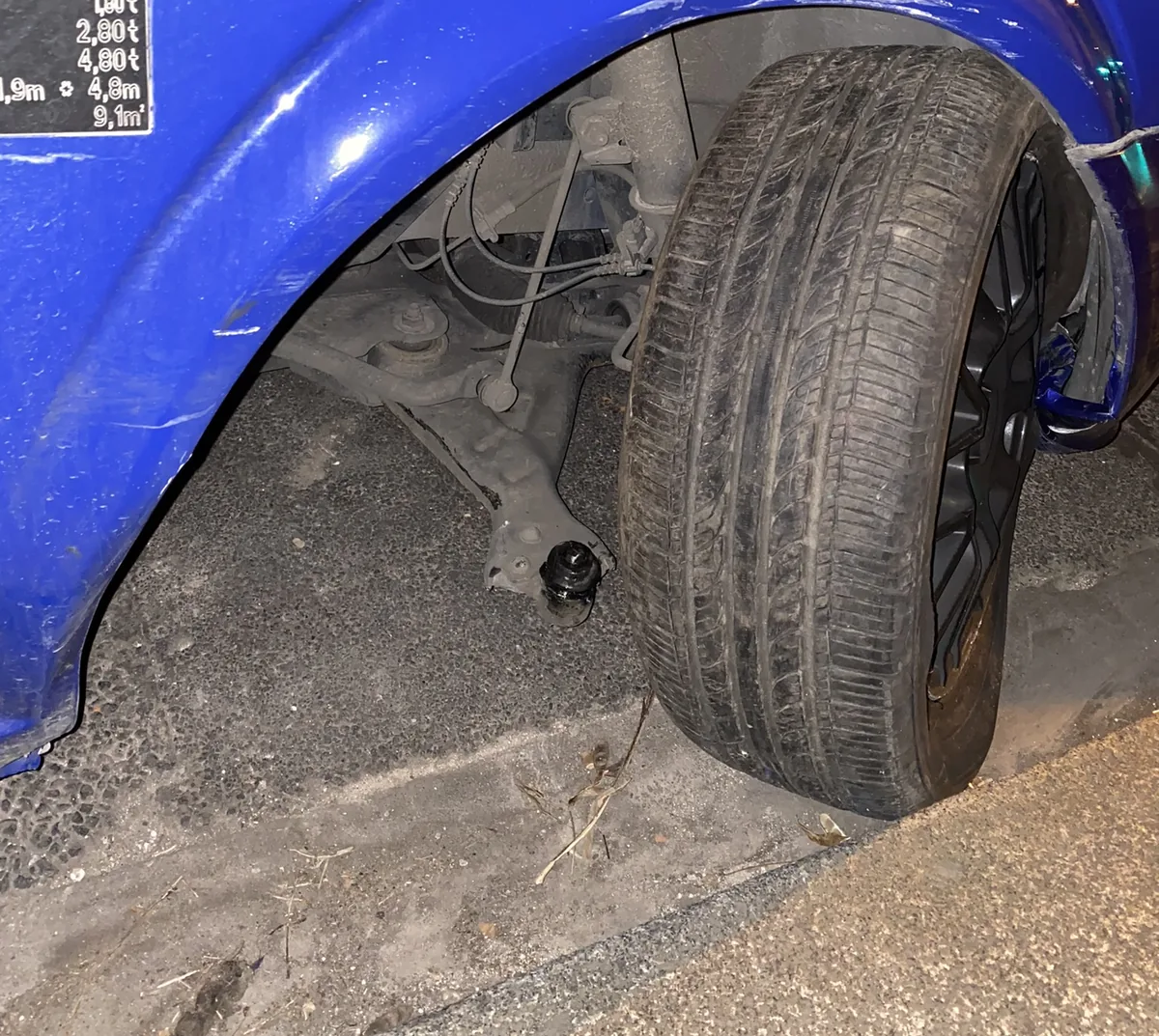 The front right wheel of a blue van leaning outward at the bottom of the wheel arch after a ball joint failure