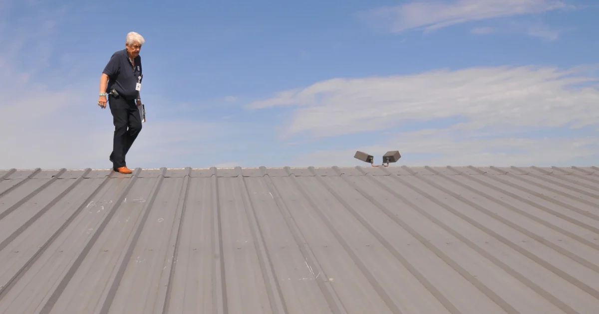 FEMA official inspecting a hail-damaged metal roof in Moore, Oklahoma.