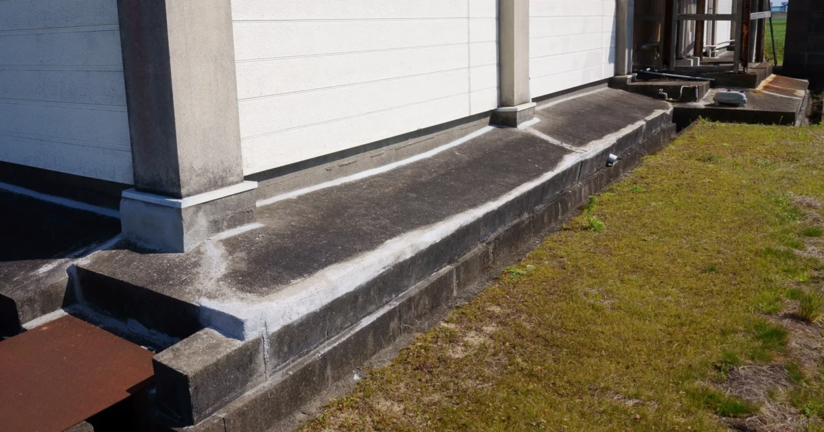 Filled cracks along the exposed concrete foundation of a warehouse.