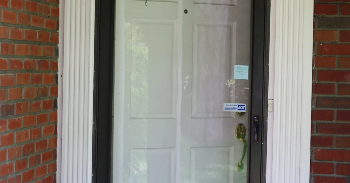 Glass storm door in a brick doorway, with the main entry door visible behind it.