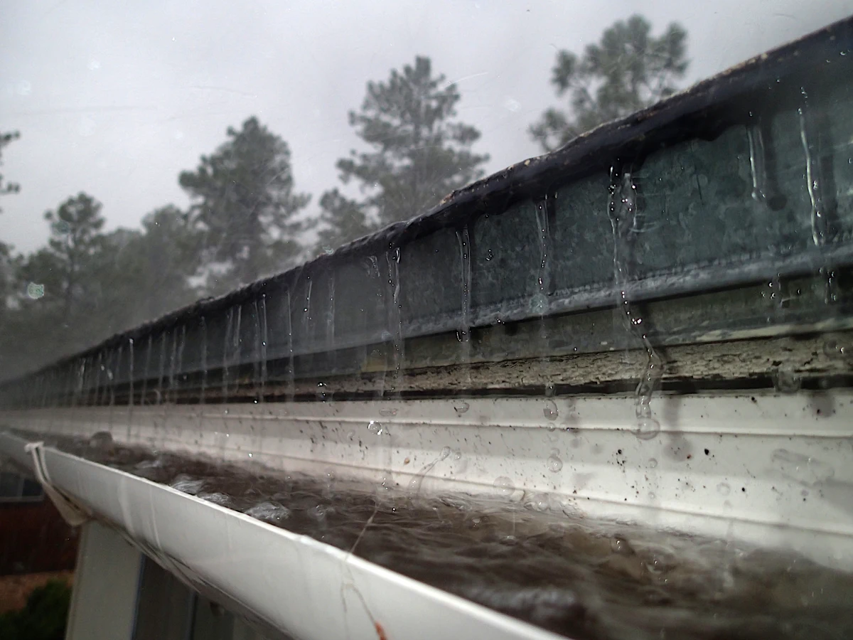 Rainwater running off a roof edge into a gutter.
